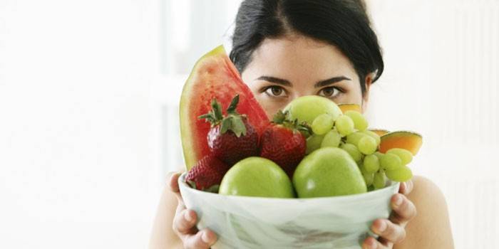 Девушка держит тарелку с фруктами