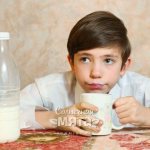 Сомневающийся мальчик пьет молоко, фото